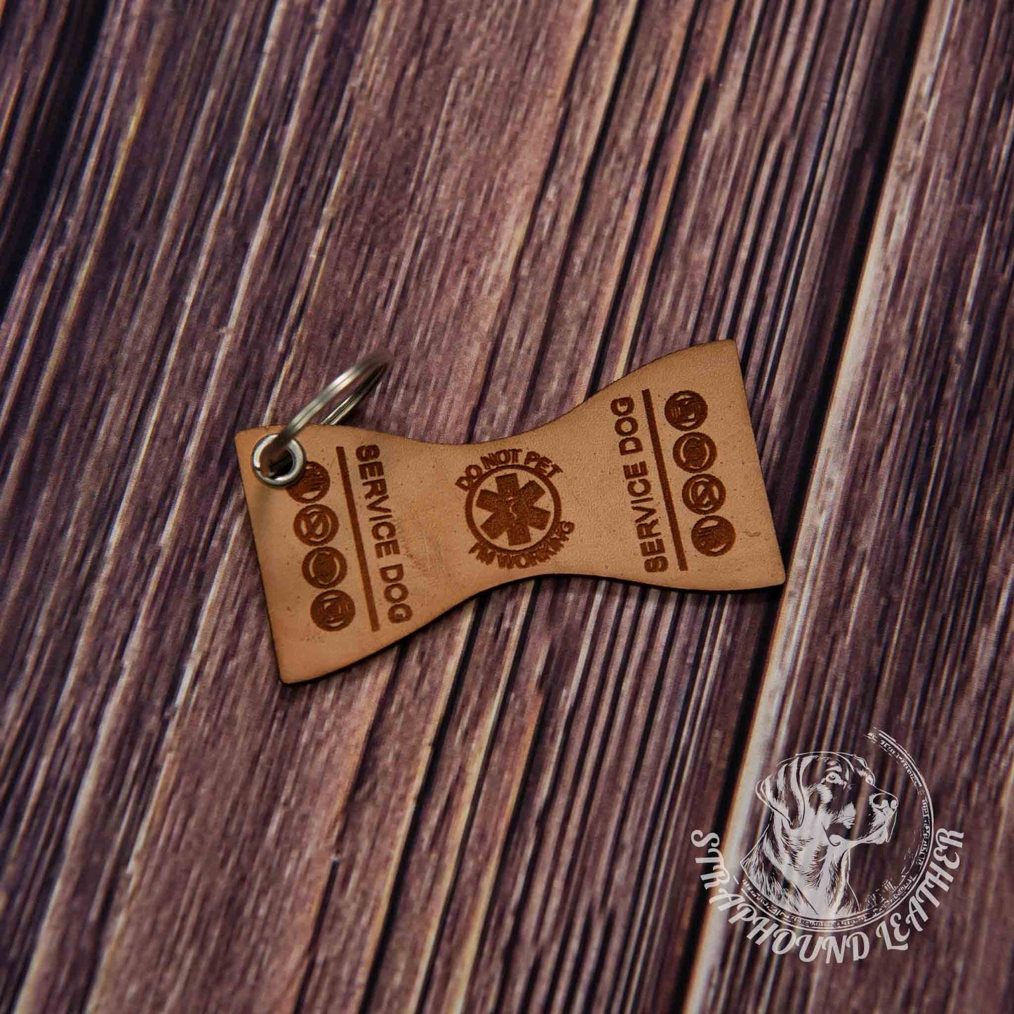 photo showing a close up of a laser engraved service dog keychain in the butterfly shape, depicting a miniature replica of service dog vest on a wood grain background