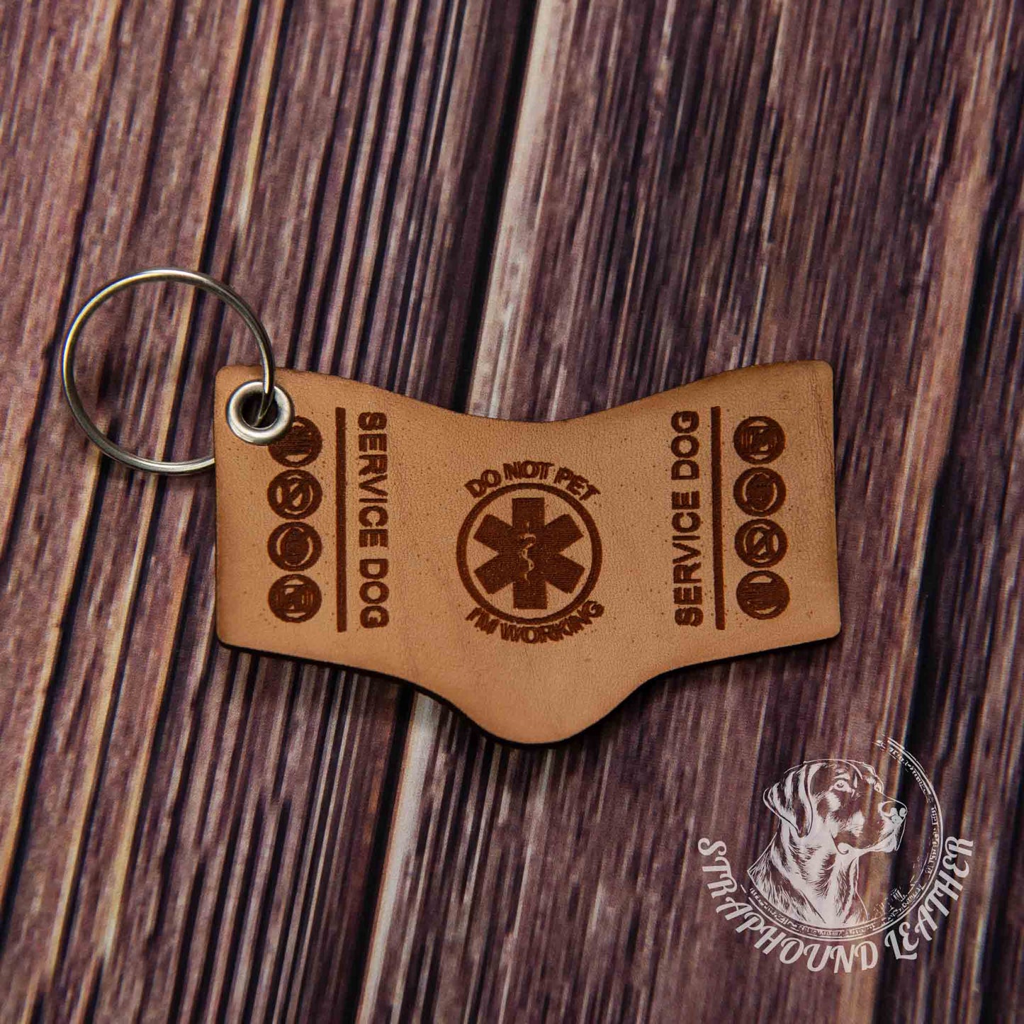 photo showing a close up of a laser engraved service dog keychain in the search and rescue shape, depicting a miniature replica of service dog vest on a wood grain background