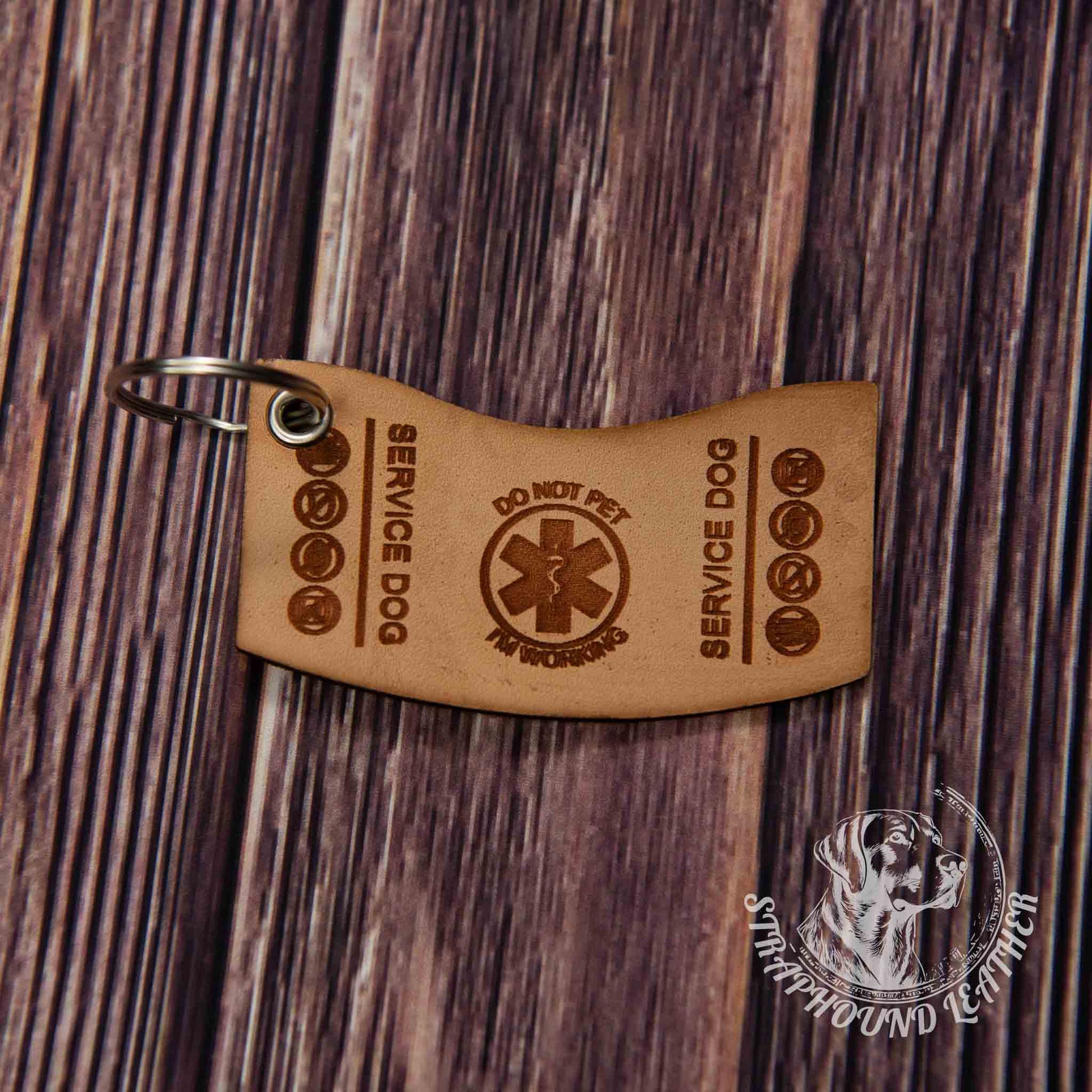 photo showing a close up of a laser engraved service dog keychain in the search and rescue short shape, depicting a miniature replica of service dog vest on a wood grain background