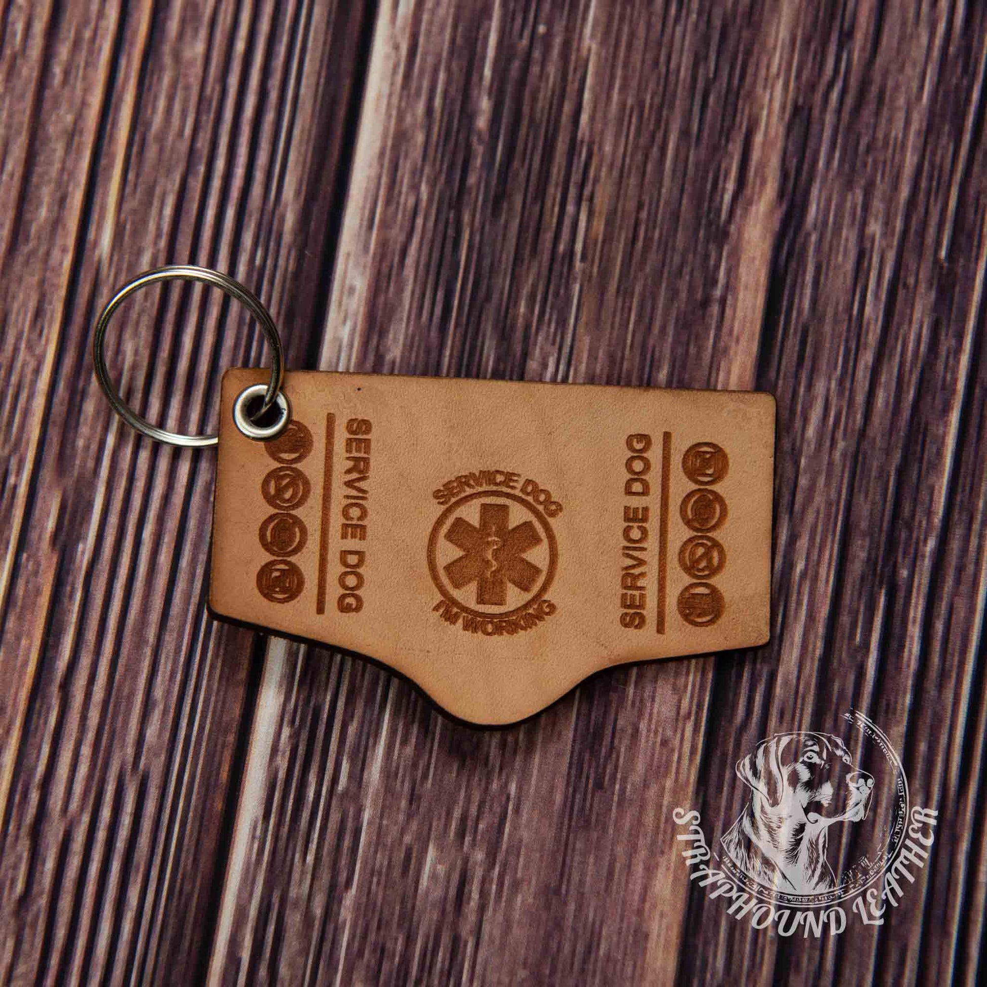 photo showing a close up of a laser engraved service dog keychain in the search and rescue long shape, depicting a miniature replica of service dog vest on a wood grain background