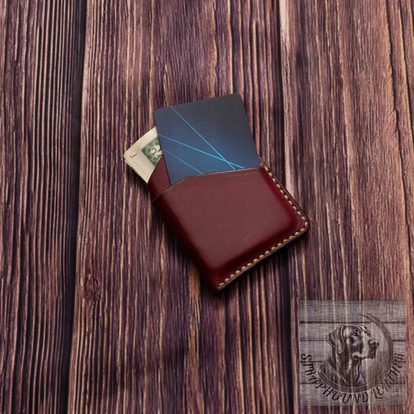 photo showing an oxblood red minimalist wallet with a light colored thread with credit card and cash.