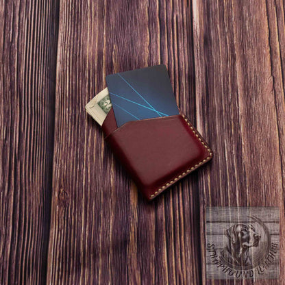 photo showing an oxblood red minimalist wallet with a light colored thread with credit card and cash.