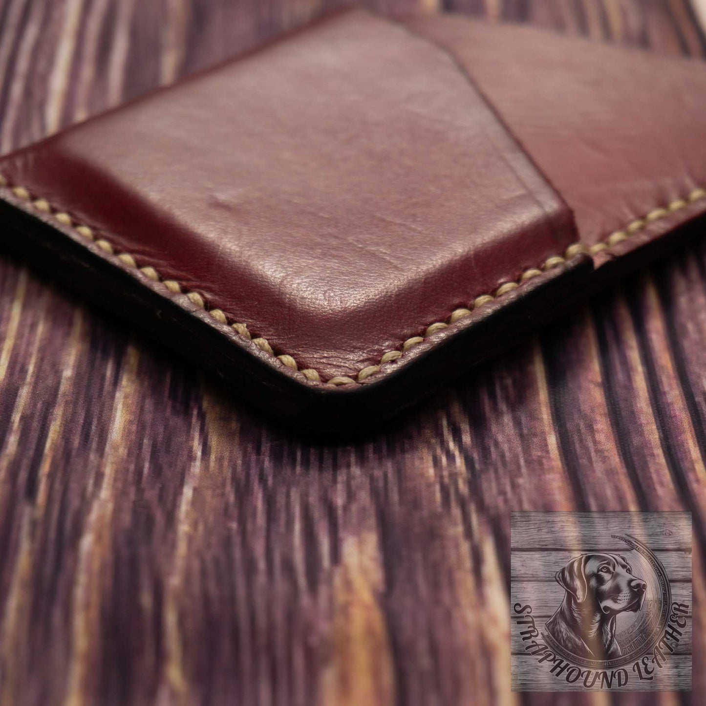 close up photo showing an oxblood red minimalist wallet with finished edge and quality of hand stitching in a light colored thread. 