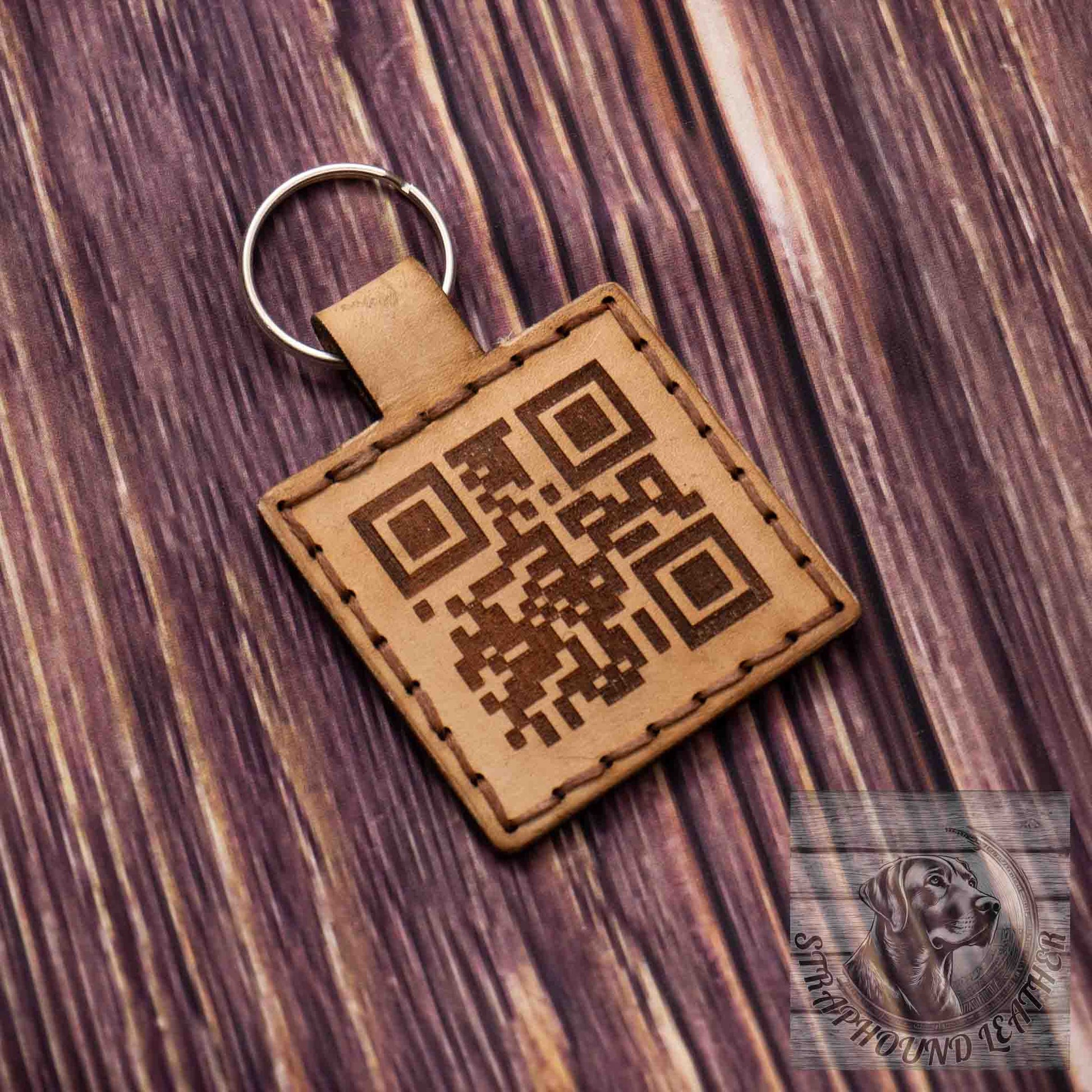 photo showing a square natural leather keychain with a QR scan-able code laser engraved on it on a wood grain background.